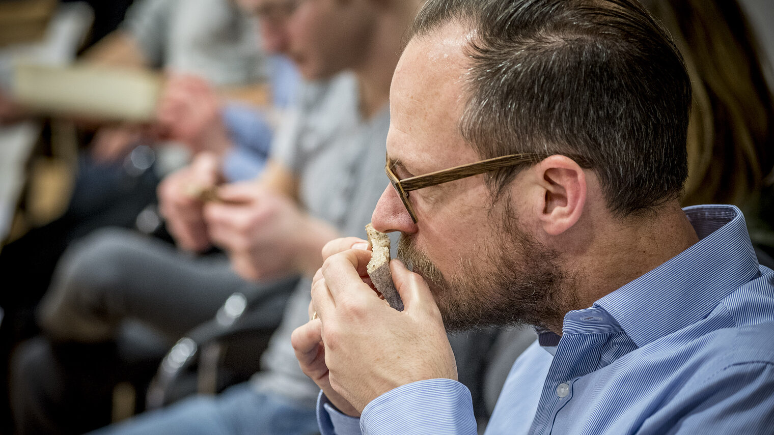 Teilnehmer der Brot-Sommelier-Weiterbildung riecht konzentriert an einem Stück Brot während einer sensorischen Prüfung