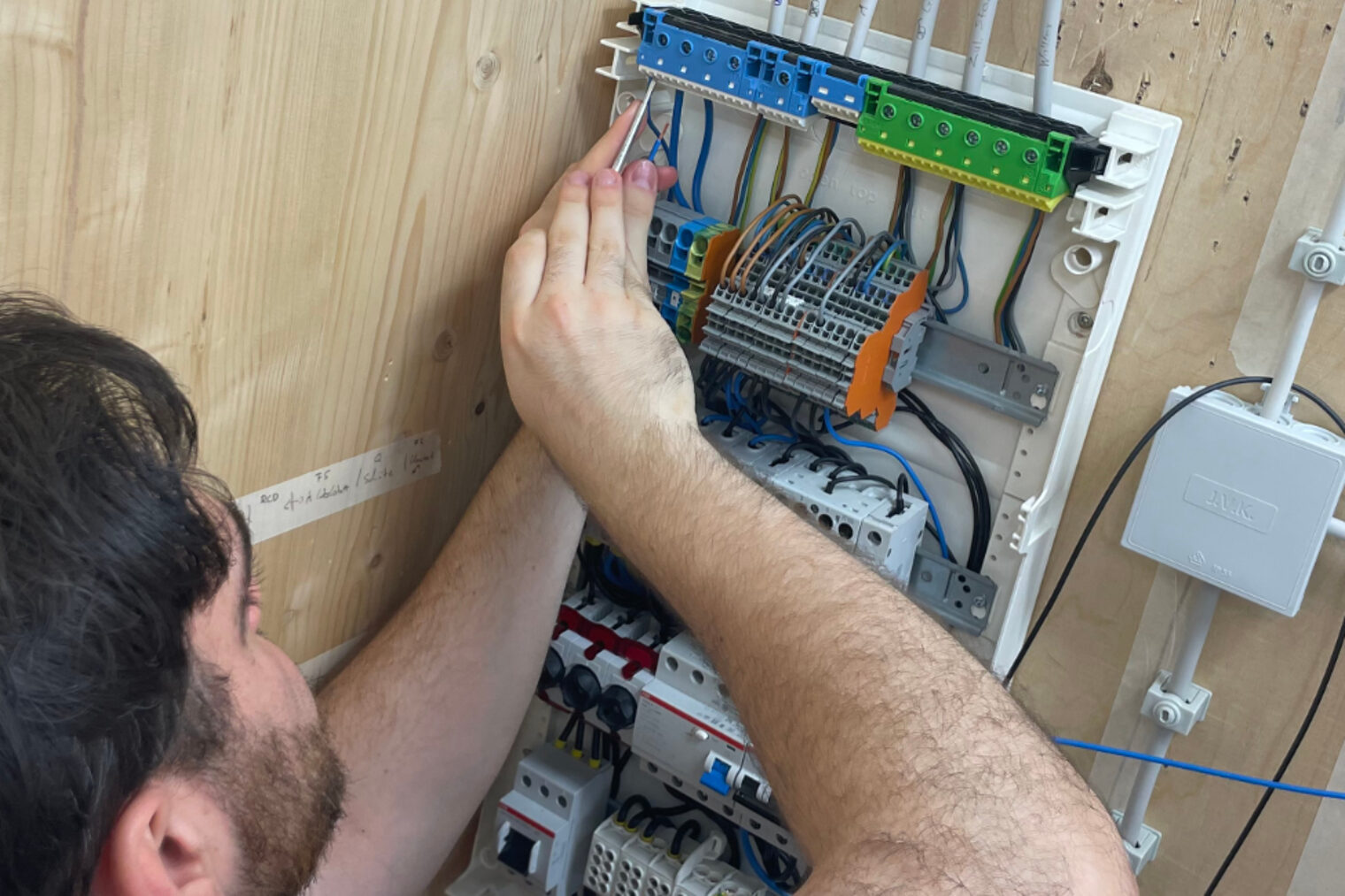 Teilnehmer der Praxiswochen installiert Verdrahtung in einem Sicherungskasten während der Vorbereitung auf die Meisterprüfung im Elektrotechnikerhandwerk