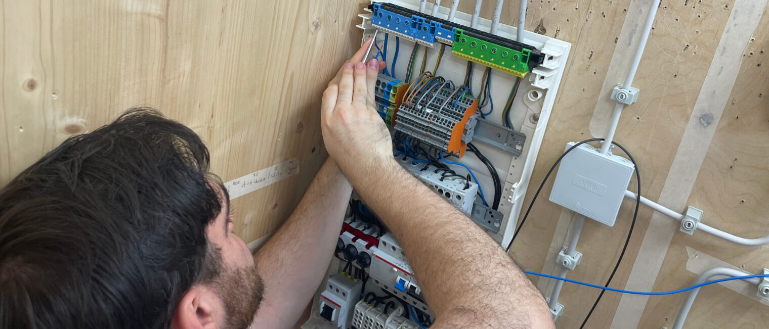 Teilnehmer der Praxiswochen installiert Verdrahtung in einem Sicherungskasten während der Vorbereitung auf die Meisterprüfung im Elektrotechnikerhandwerk