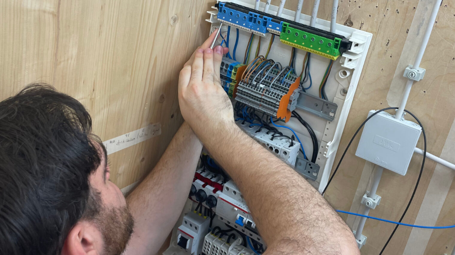 Teilnehmer der Praxiswochen installiert Verdrahtung in einem Sicherungskasten während der Vorbereitung auf die Meisterprüfung im Elektrotechnikerhandwerk