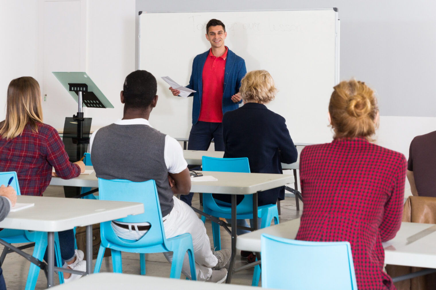 Dozent hält Schulung vor Erwachsenen in einem Seminarraum mit Whiteboard