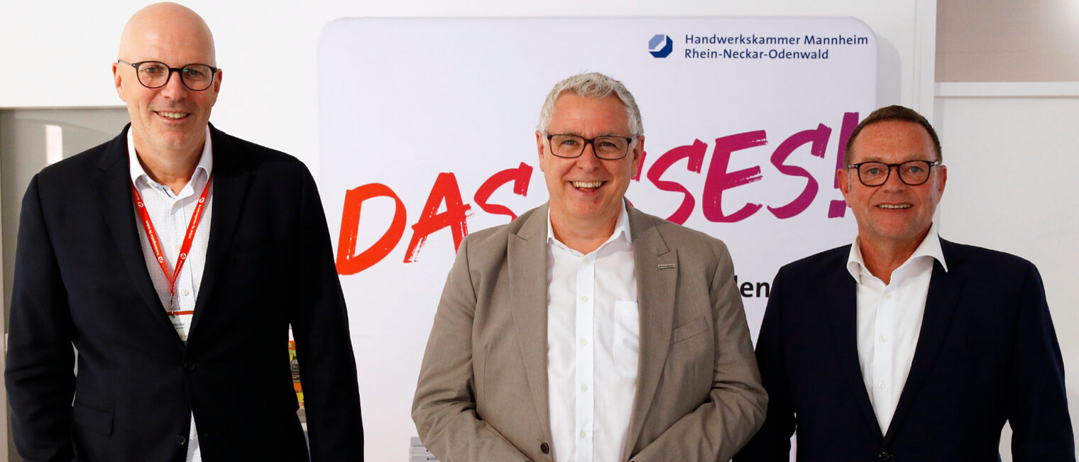 Drei Männer stehen lächelnd vor einem Banner der Handwerkskammer Mannheim Rhein-Neckar-Odenwald (v.l.): Norbert Hölscher (Bundesagentur für Arbeit), Thorsten Riehle (Wirtschaftsbürgermeister Mannheim), Klaus Hofmann (Kammerpräsident).