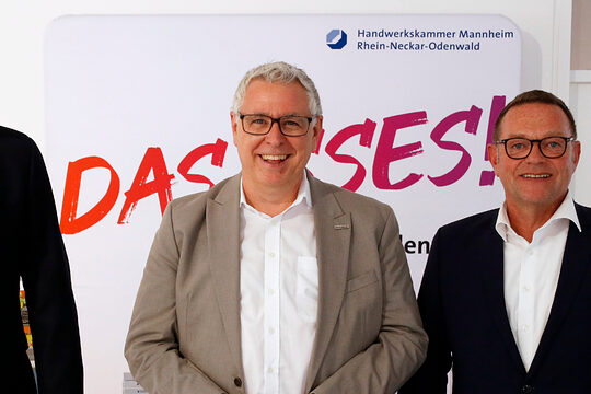 Drei Männer stehen lächelnd vor einem Banner der Handwerkskammer Mannheim Rhein-Neckar-Odenwald (v.l.): Norbert Hölscher (Bundesagentur für Arbeit), Thorsten Riehle (Wirtschaftsbürgermeister Mannheim), Klaus Hofmann (Kammerpräsident).