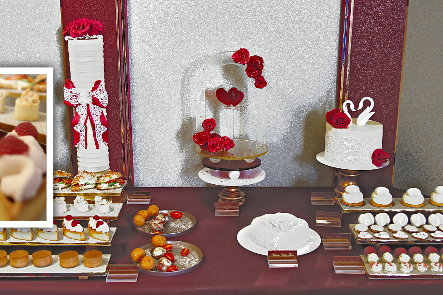 Konditoren-Buffet „Royal Wedding": weißer Baumkuchen mit Rosendekor, Glas-Schaustück mit roten Rosen und Herz, Hochzeitstorte mit Schwanenpaar, herzförmige Pralinen und Mini-Torten; im Ausschnitt Törtchen mit Beeren und Sahne.