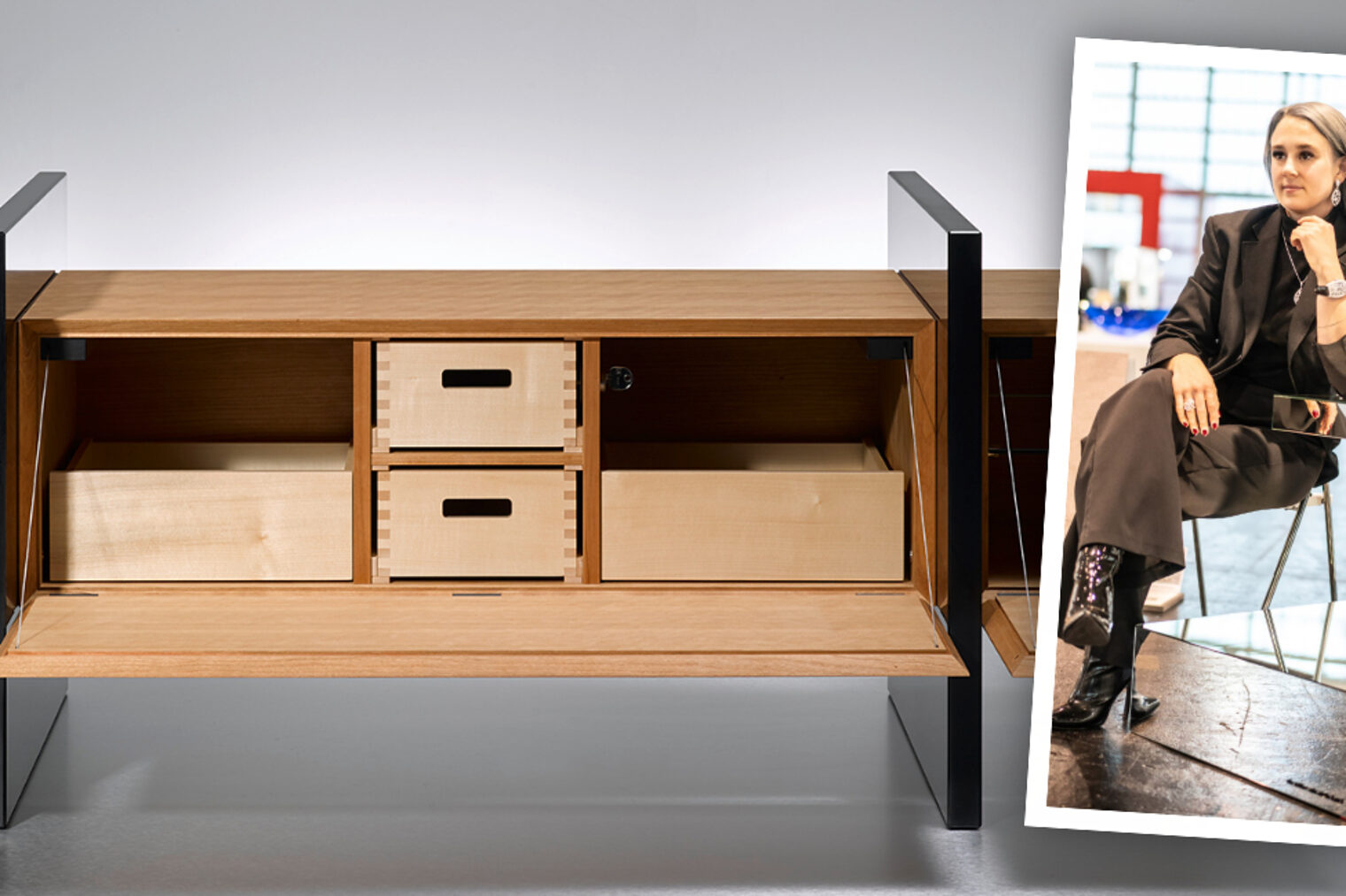 Schreinerin Nicole Doth sitzt neben ihrer Spiegelskulptur; links das geöffnete Holz-Sideboard „3hoch2“ mit schwarzen Seitenwangen.